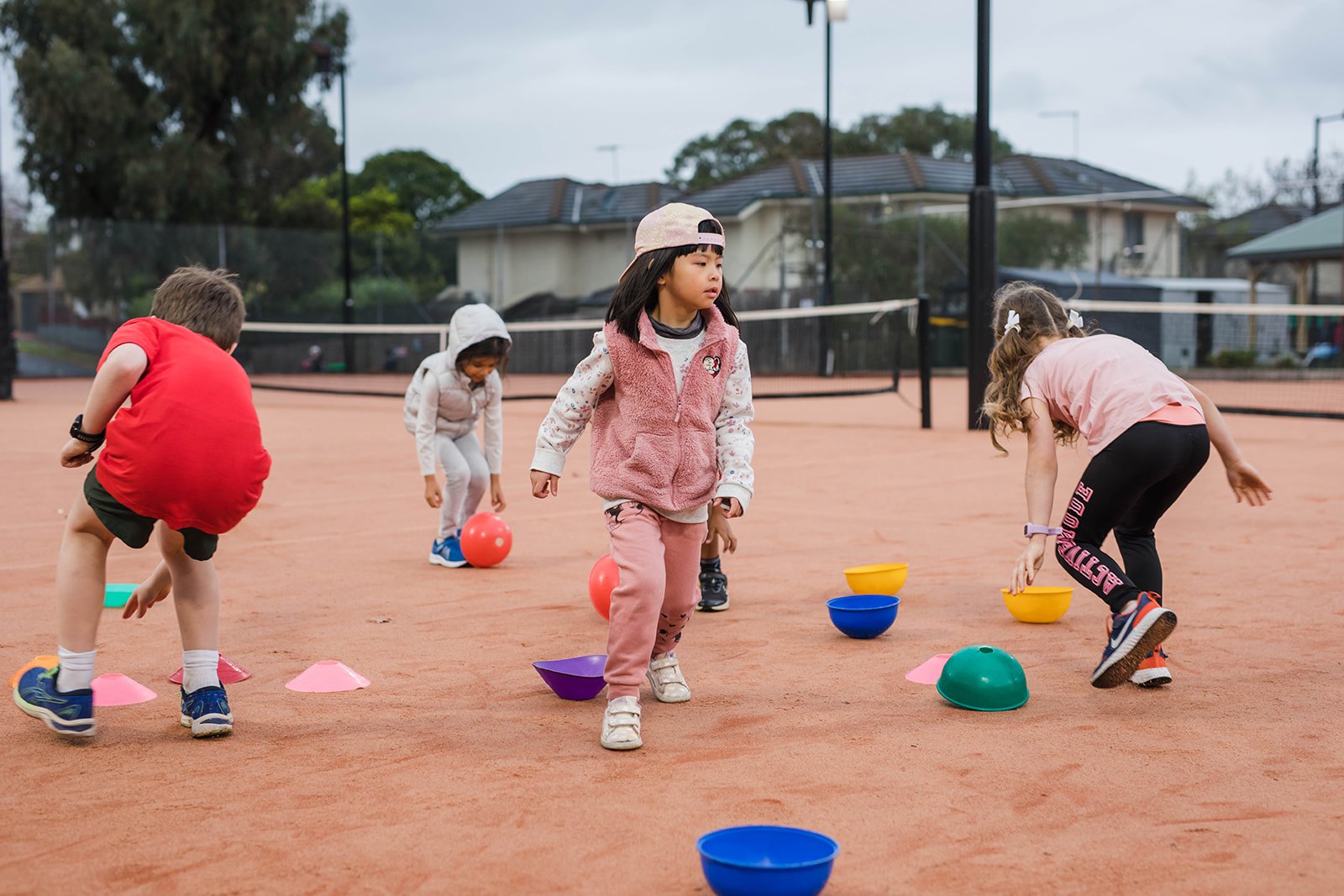 Hot Shots kids chasing coloured balls between cones on a clay court