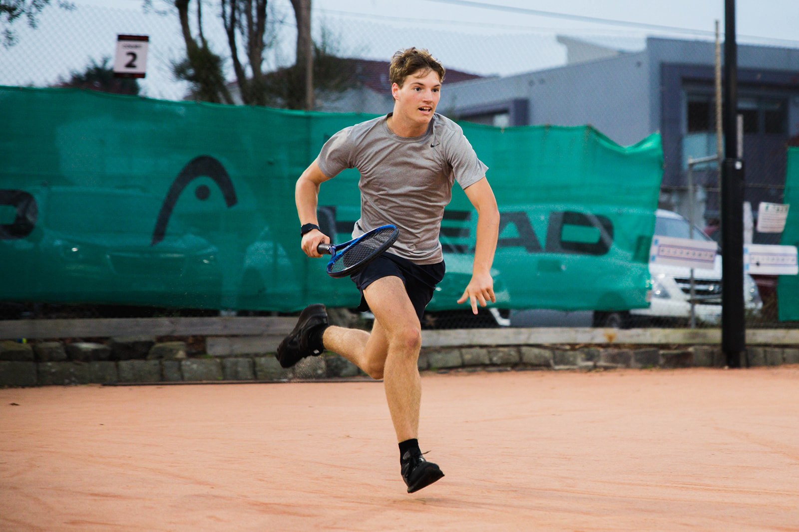 A junior lunging for a wide ball on the clay