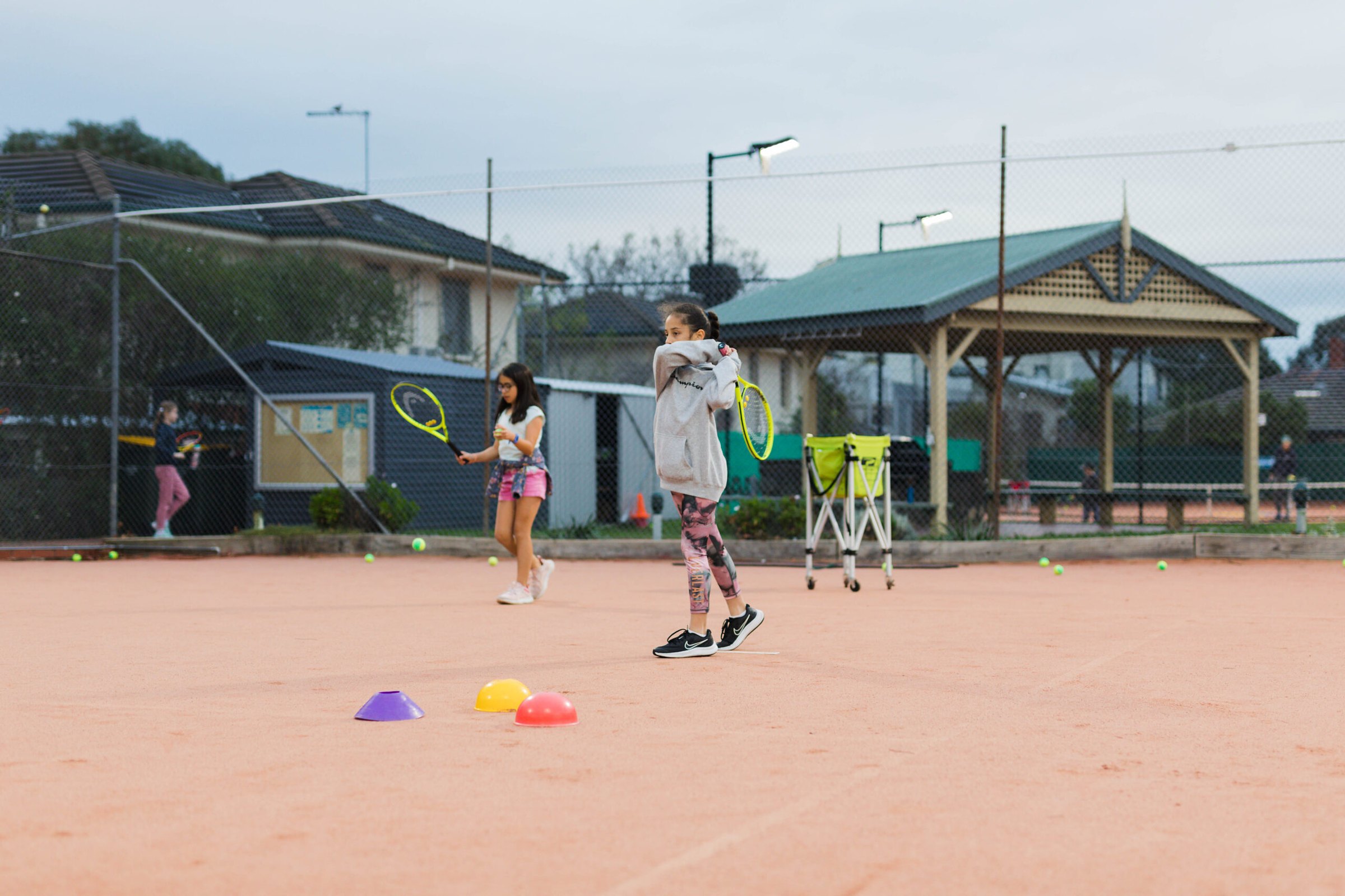 Young players rallying with red balls on the clay at Box Hill
